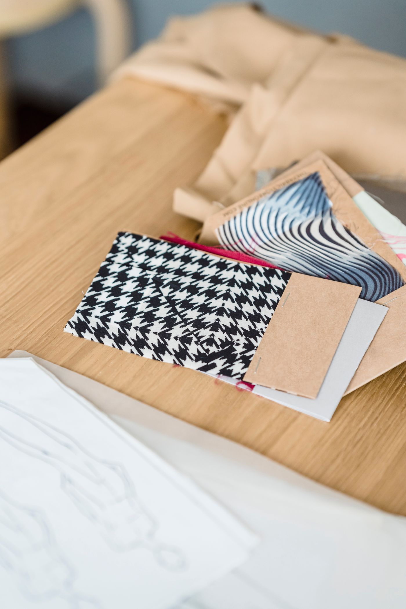 Real checked and striped fabric swatches beside sketches on a wooden table